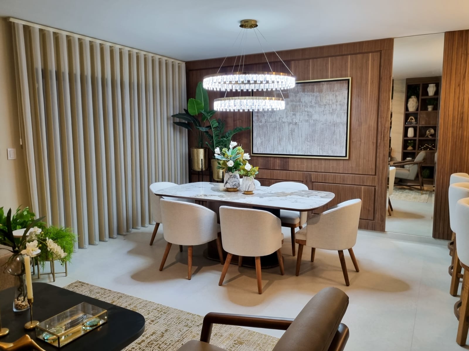 Comedor de casa muestra con muro de madera, lámpara de anillos y sillas tapizadas